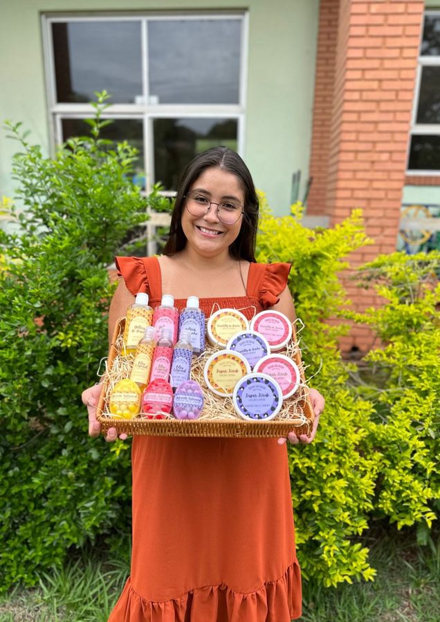 Camila com a bandeja da produção dela: geleia de banho, óleo corporal, chantilly e sabonetes